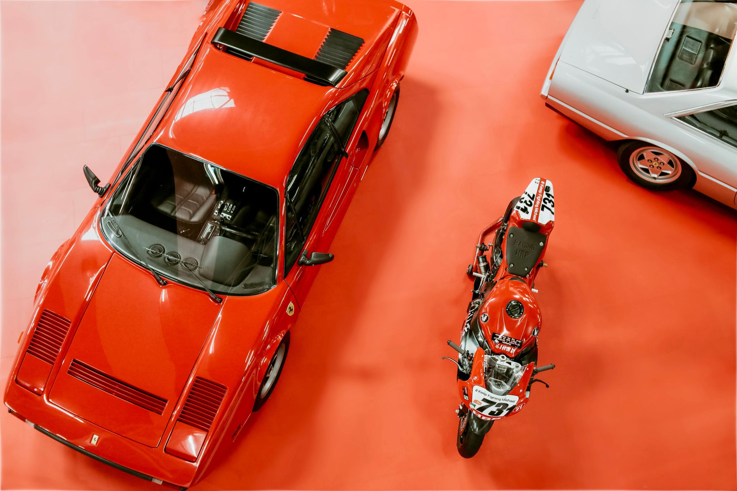 High angle shot of classic Ferrari and motorcycle on display at an aut