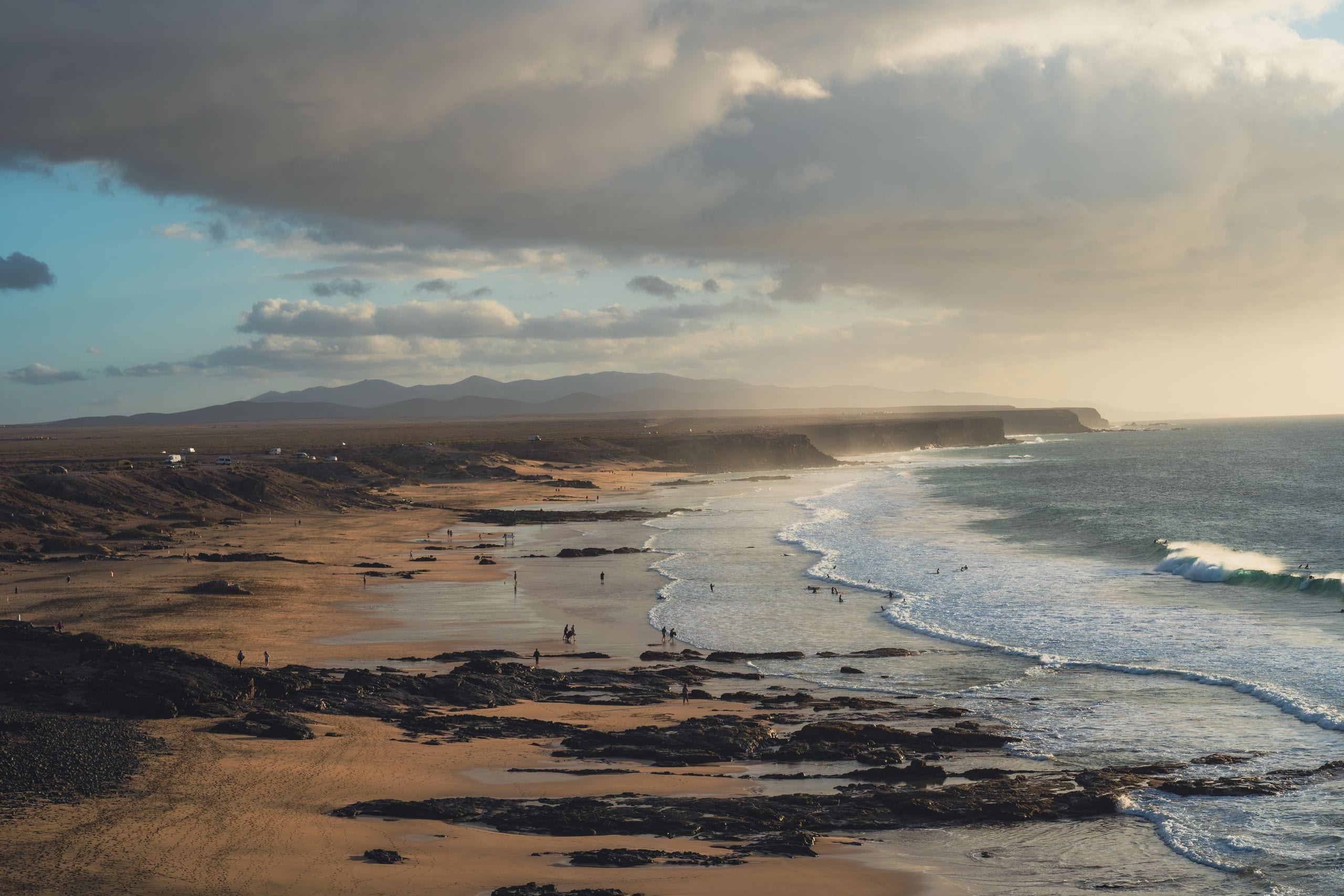 An expansive beach with dramatic waves under a cloudy sky, perfect for