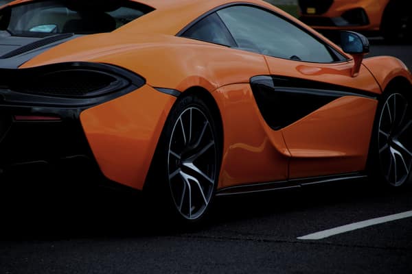 A dynamic shot of an orange sports car on a road in England, United Ki