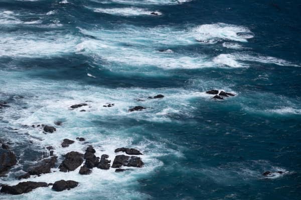 Dynamic aerial shot of the Pacific Ocean waves crashing over rocks in 