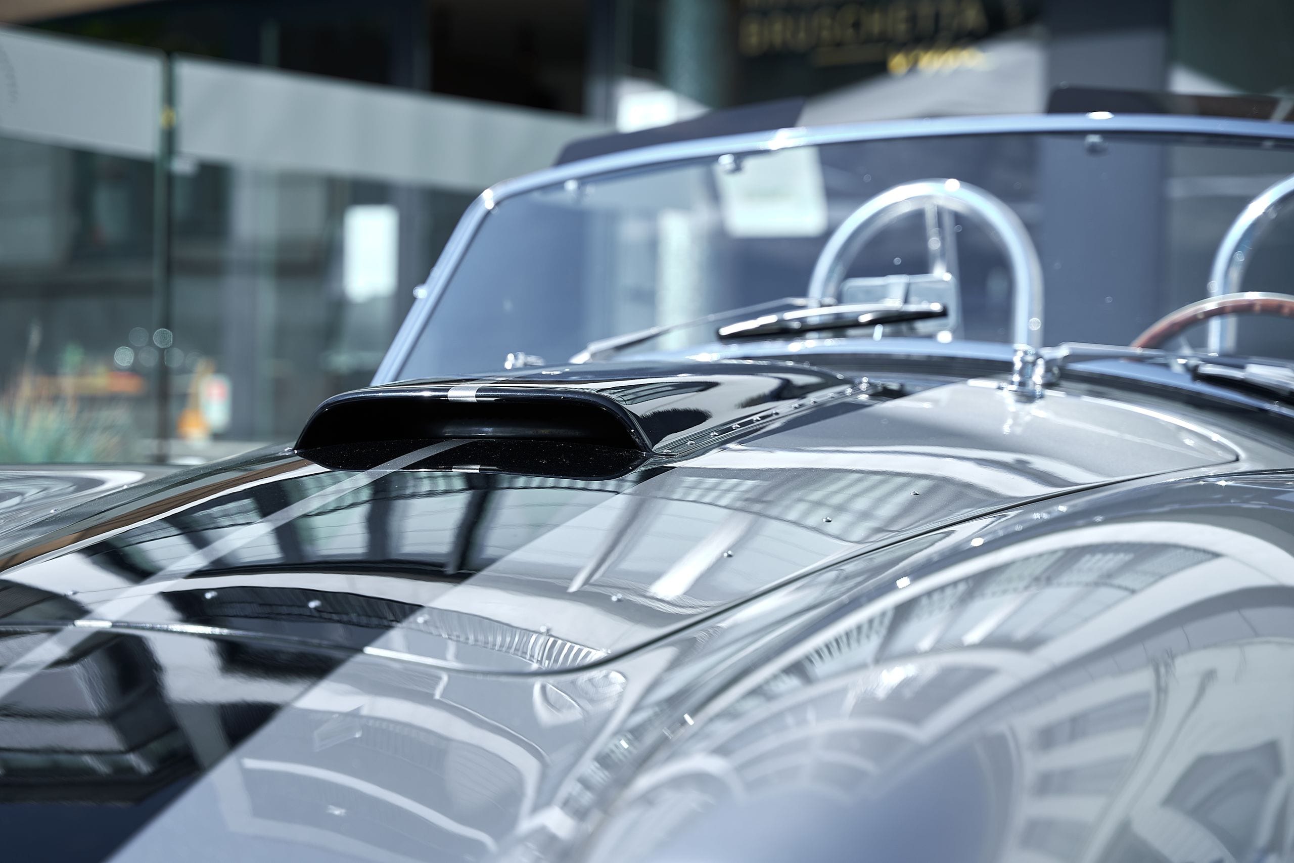 Close-up of a modern car hood reflecting light in a sunlit indoor sett