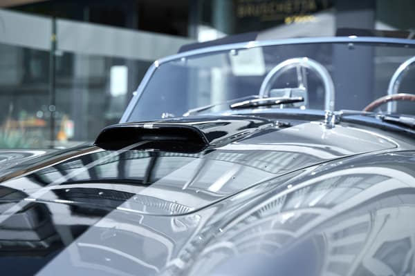 Close-up of a modern car hood reflecting light in a sunlit indoor sett