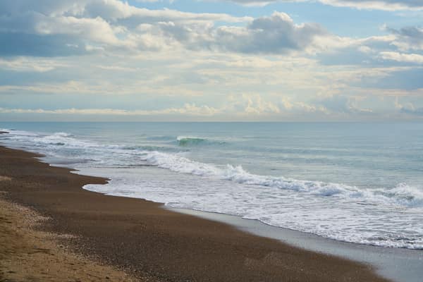Peaceful beach scene with gentle waves and a cloudy sky, perfect for r