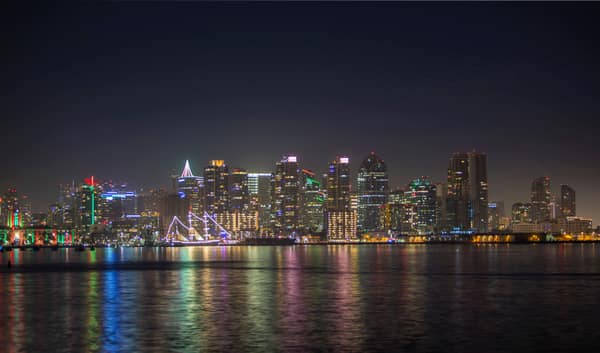 Vibrant nighttime cityscape with illuminated skyscrapers reflecting on