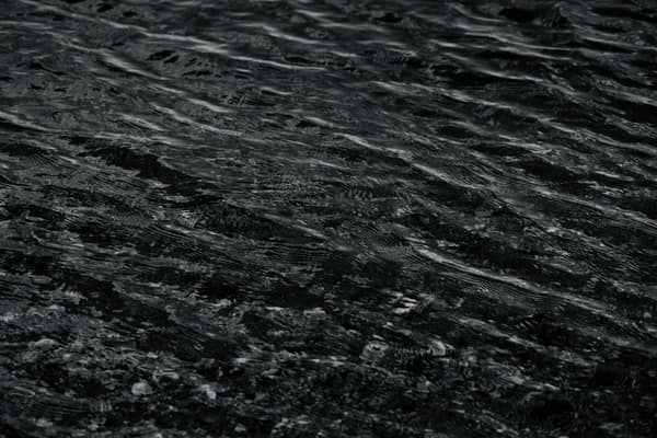 A moody close-up of dark wavy water texture, showcasing natural patter