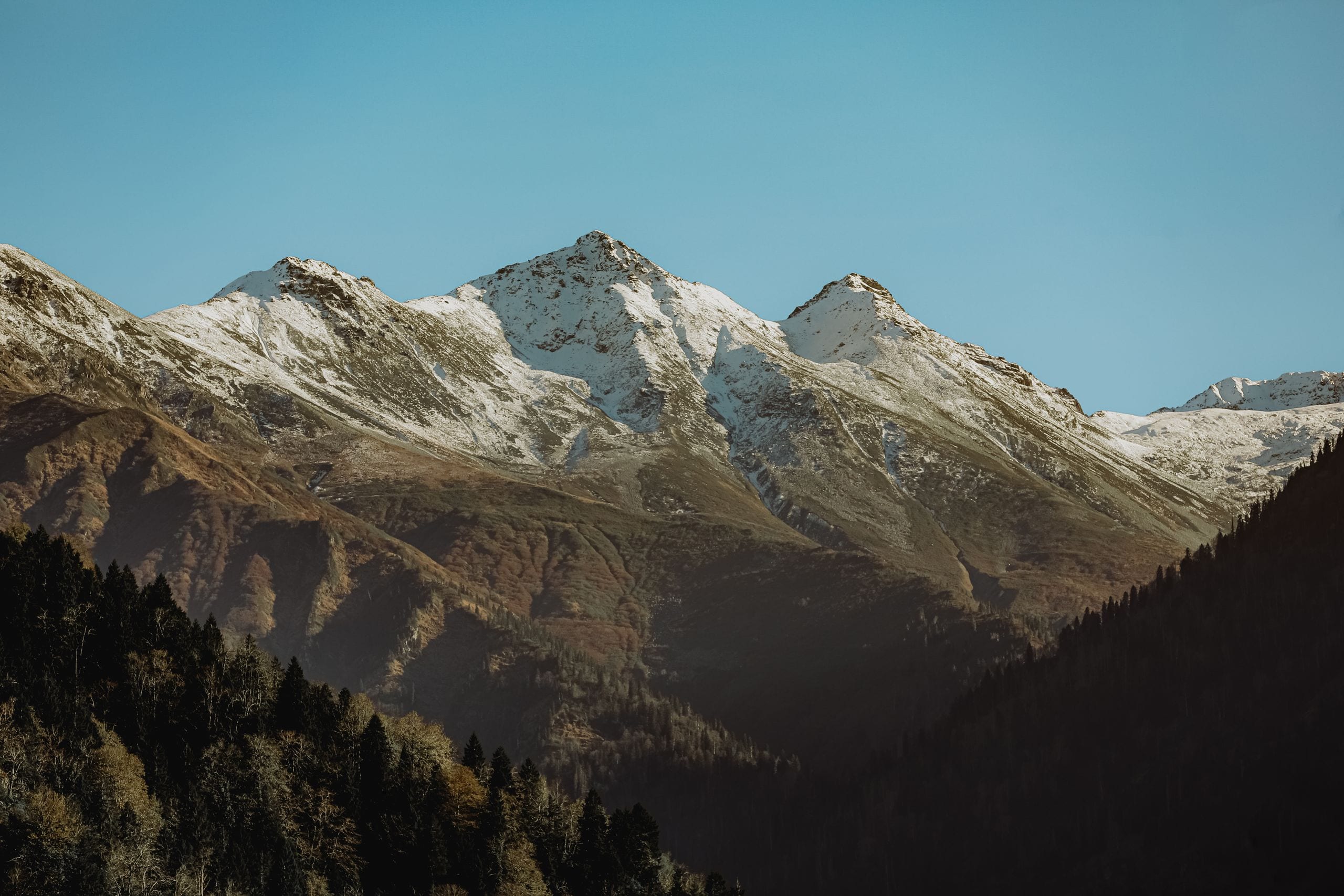 A picturesque view of snow-capped mountains under a clear blue sky.