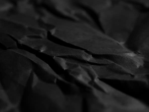 A close-up of crumpled black paper texture creating a dramatic abstrac