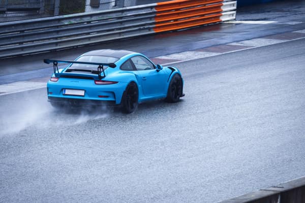 A sports car speeds on a wet racetrack, showcasing adrenaline and prec