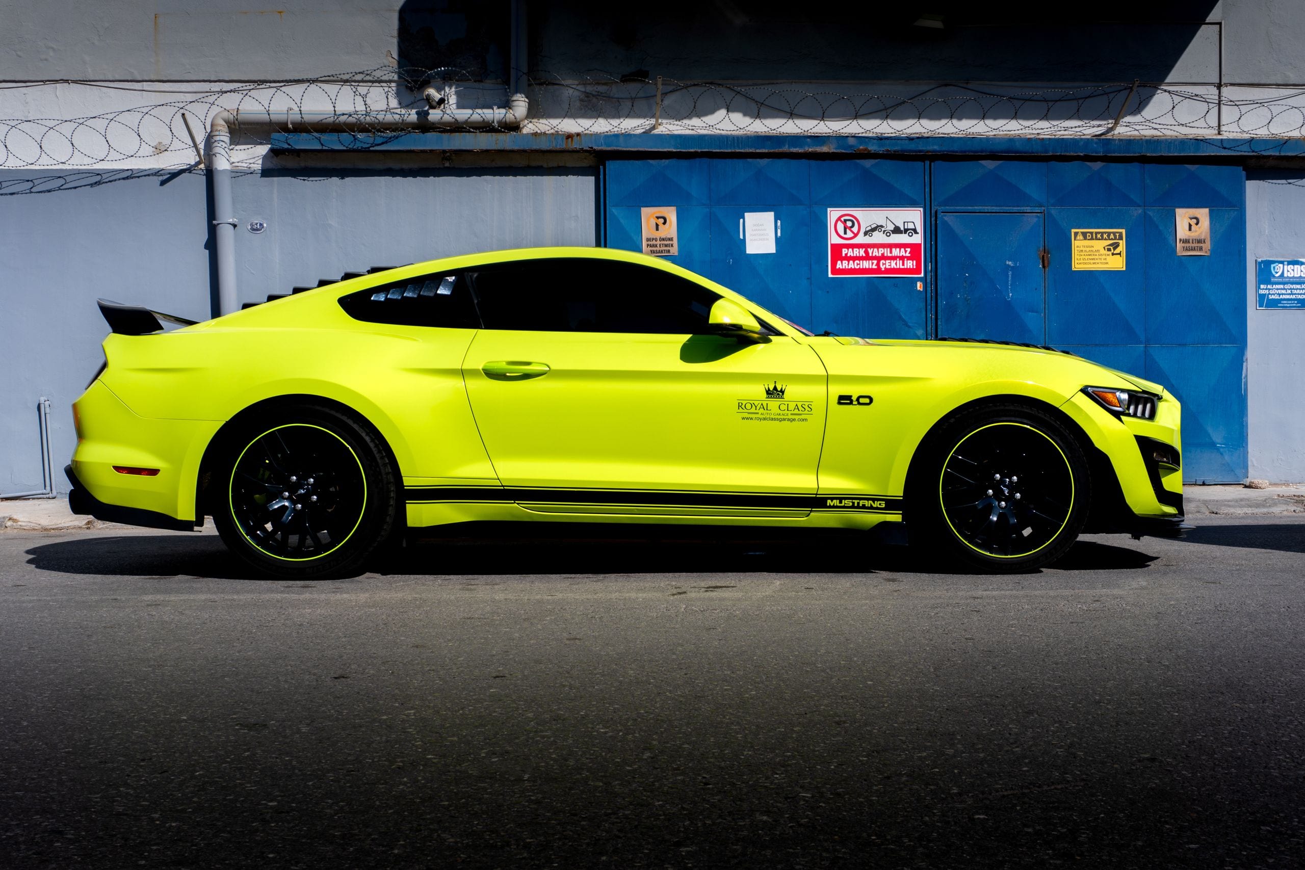 A sleek yellow sports car parked against an industrial backdrop in Tür