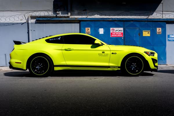 A sleek yellow sports car parked against an industrial backdrop in Tür