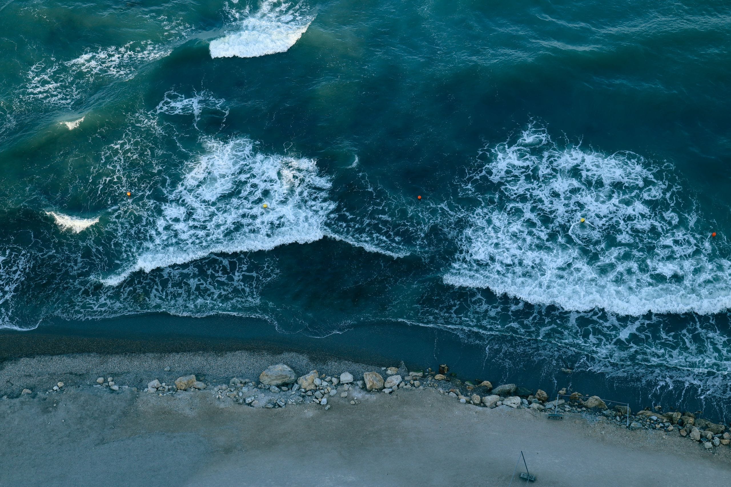 Aerial shot of ocean waves crashing against a rocky shoreline, creatin