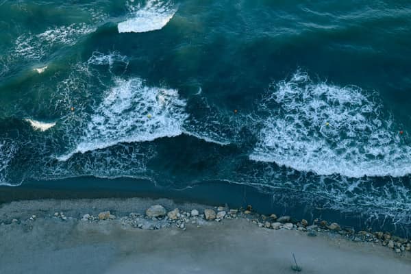 Aerial shot of ocean waves crashing against a rocky shoreline, creatin