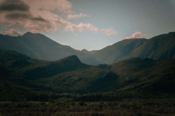 A peaceful view of mountains with lush greenery under a cloudy sky, ev