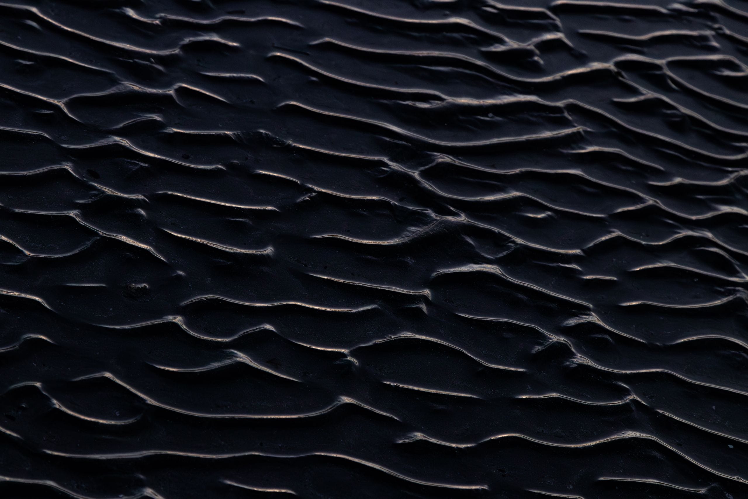 Close-up view of dark sand ripples creating a unique abstract texture