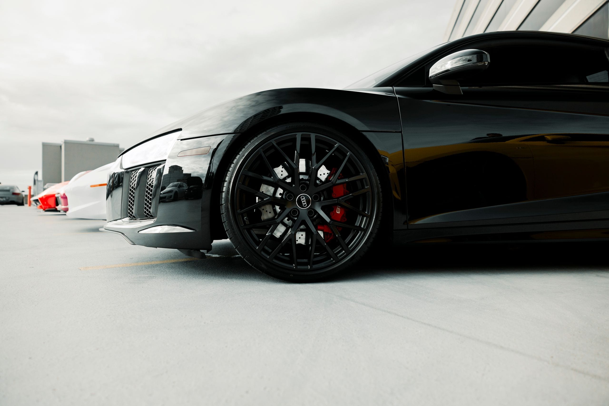 Close-up of a black luxury sports car's wheel detail in an outdoor set
