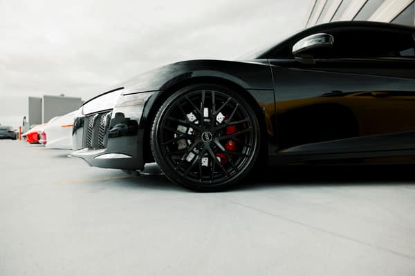 Close-up of a black luxury sports car's wheel detail in an outdoor set