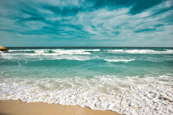 Idyllic beach with turquoise waves and clear sky. Perfect for travel t