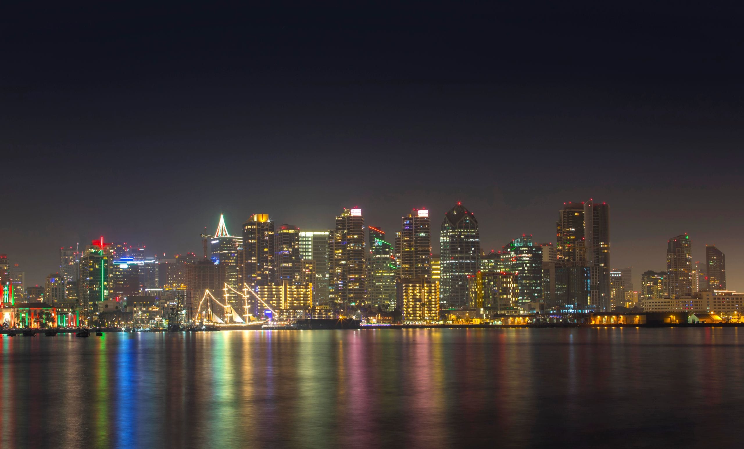 A serene night view of San Diego's illuminated skyline reflecting on c