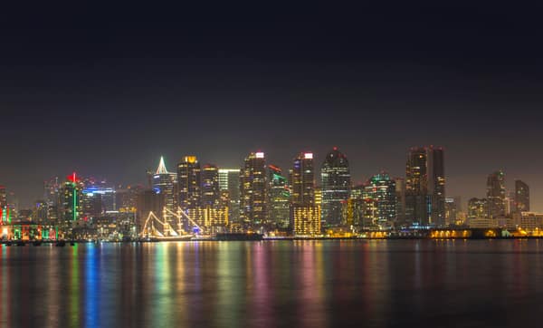 A serene night view of San Diego's illuminated skyline reflecting on c