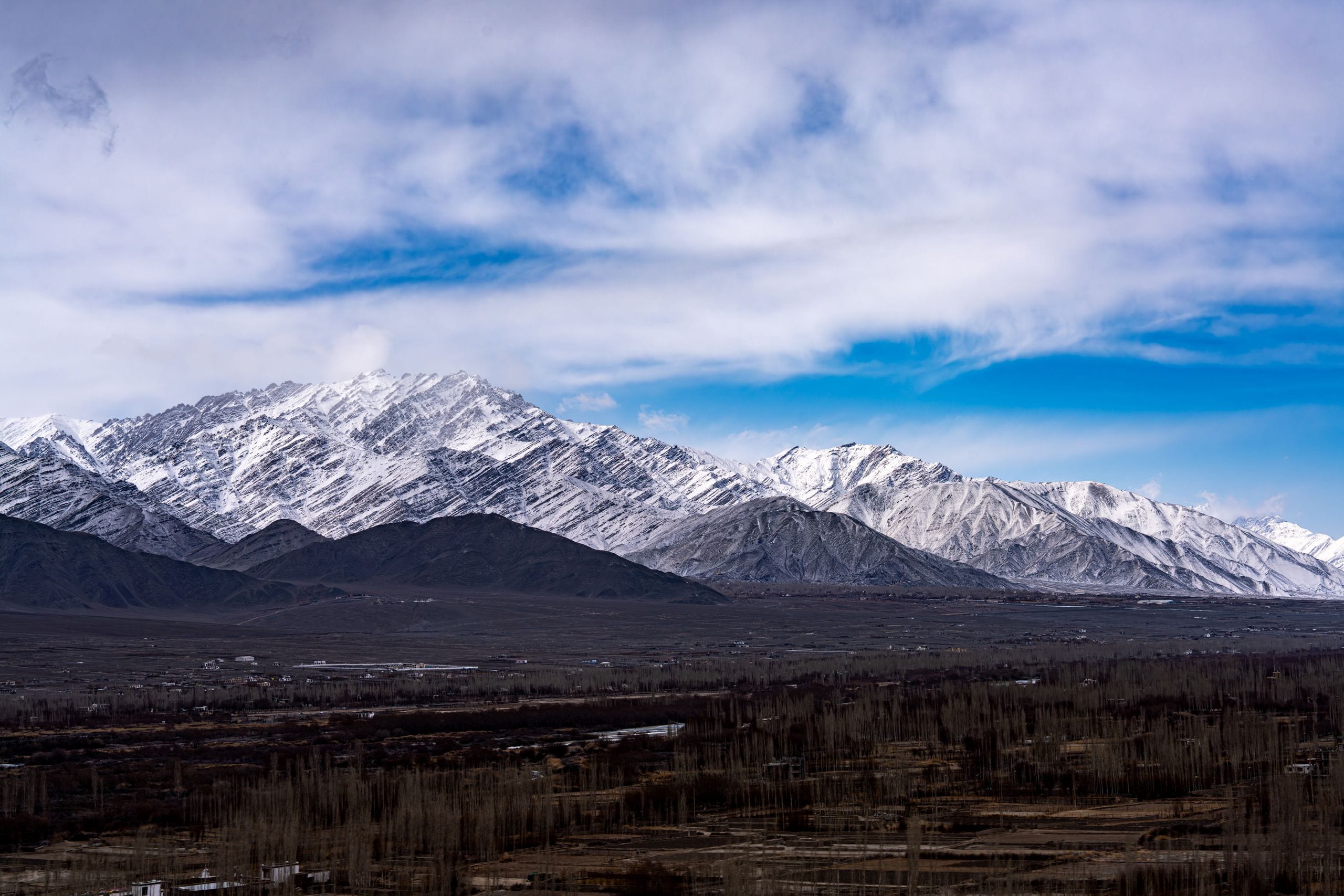 Majestic snow-capped mountains stretch under a vibrant blue sky, showc