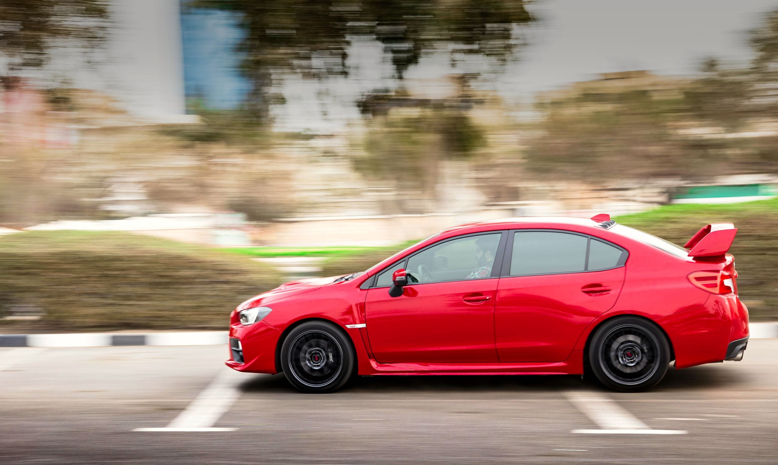 Red sports car in motion on a city road with a blurred background, sho