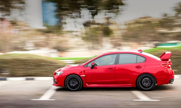 Red sports car in motion on a city road with a blurred background, sho