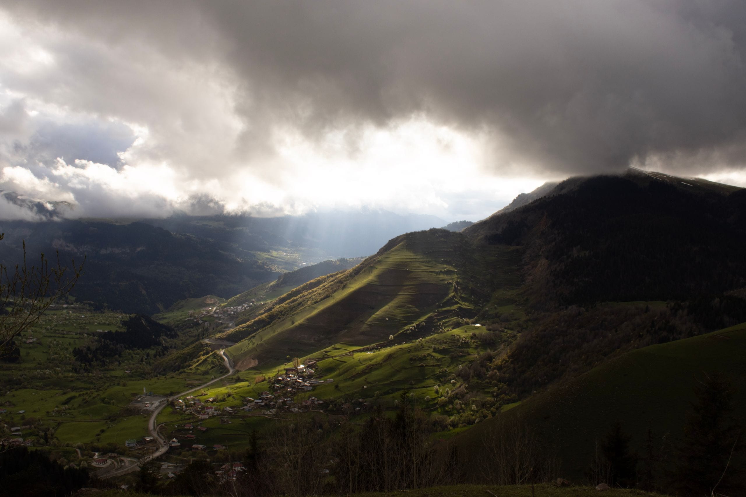 A stunning mountain valley scene with dramatic clouds and sunbeams bre