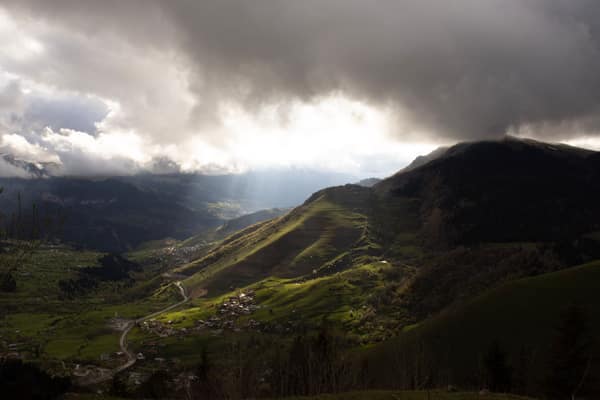 A stunning mountain valley scene with dramatic clouds and sunbeams bre