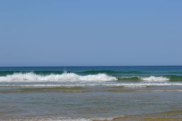 Calm ocean waves gently crashing on a sandy beach under a clear blue s