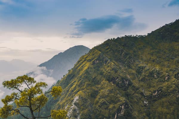 A breathtaking view of lush green mountain hills under a blue sky, per