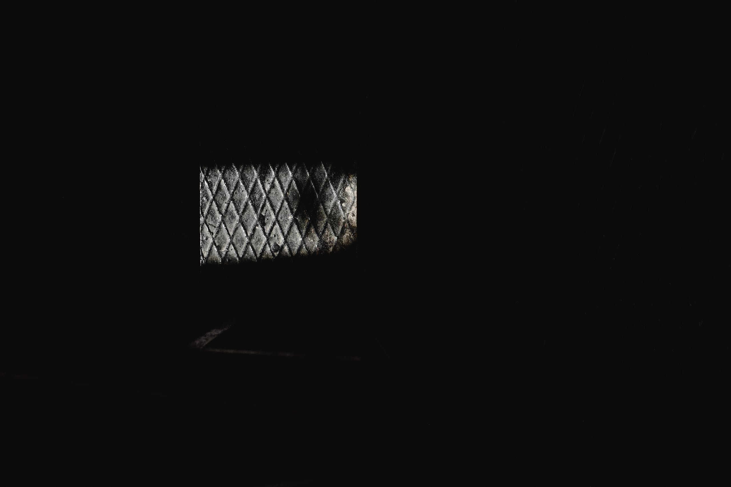 A dimly lit diamond-patterned window in a dark room, showcasing minima