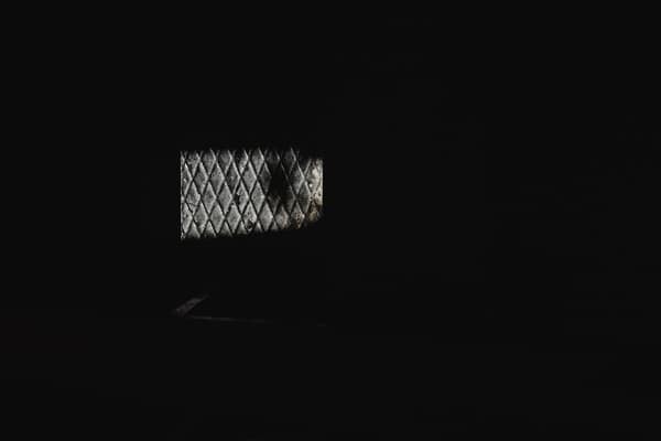 A dimly lit diamond-patterned window in a dark room, showcasing minima