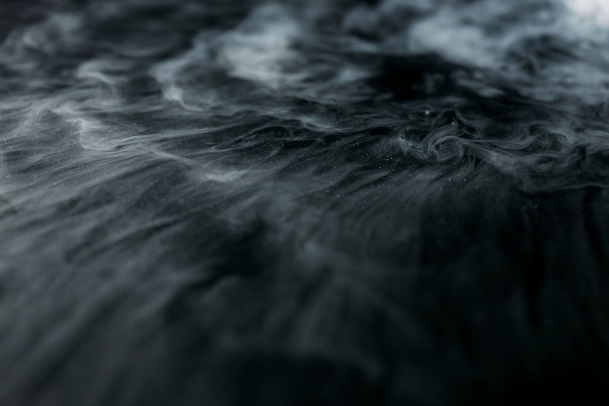 Enigmatic swirling smoke over a dark surface creating a mysterious amb