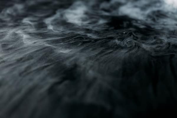 Enigmatic swirling smoke over a dark surface creating a mysterious amb