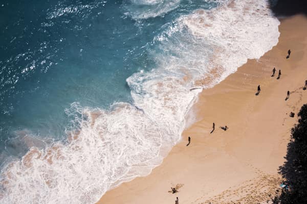 A stunning aerial view of a Bali beach with turquoise waters and crash